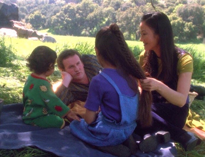 Kirayoshi, Miles, Molly, and Keiko O'Brien enjoying a picnic outside in a grassy area in 'Time's Orphan'