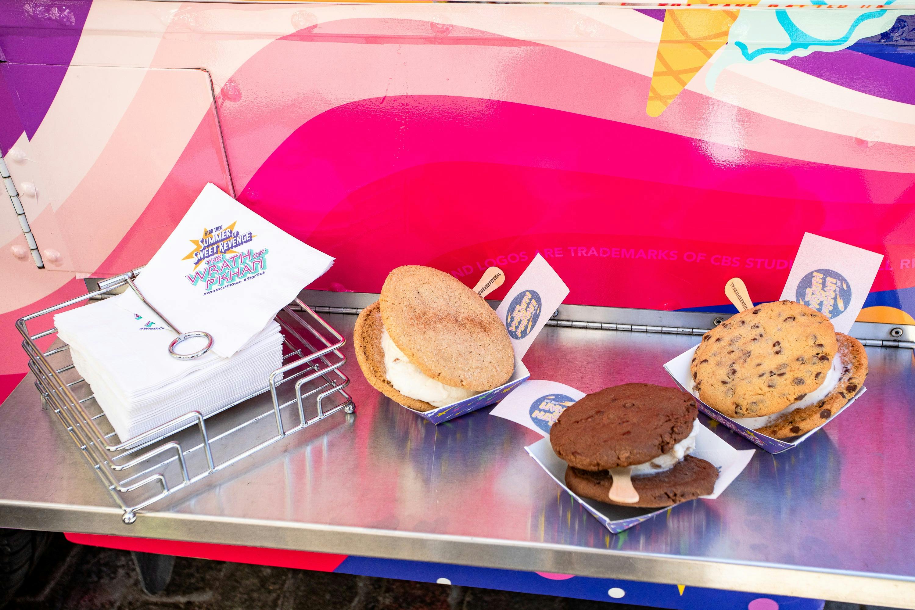 Three ice cream sandwiches sit on a metal ledge on the truck.