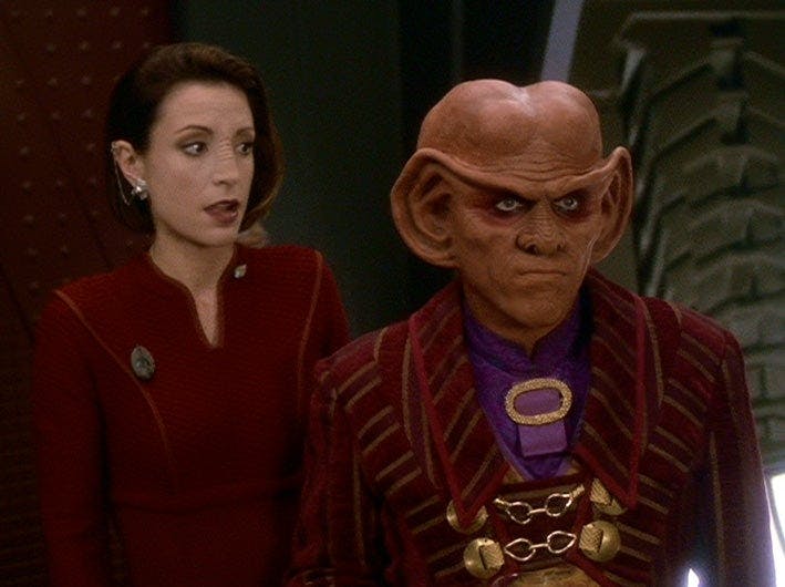 Kira looks over at Quark who watches Odo leave without saying goodbye on Star Trek: Deep Space Nine