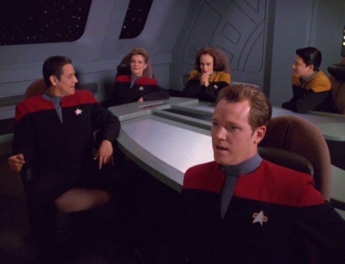 The Voyager crew sit around the table and analyze the simulation of Tom Paris hitting Warp 10 on Star Trek: Voyager
