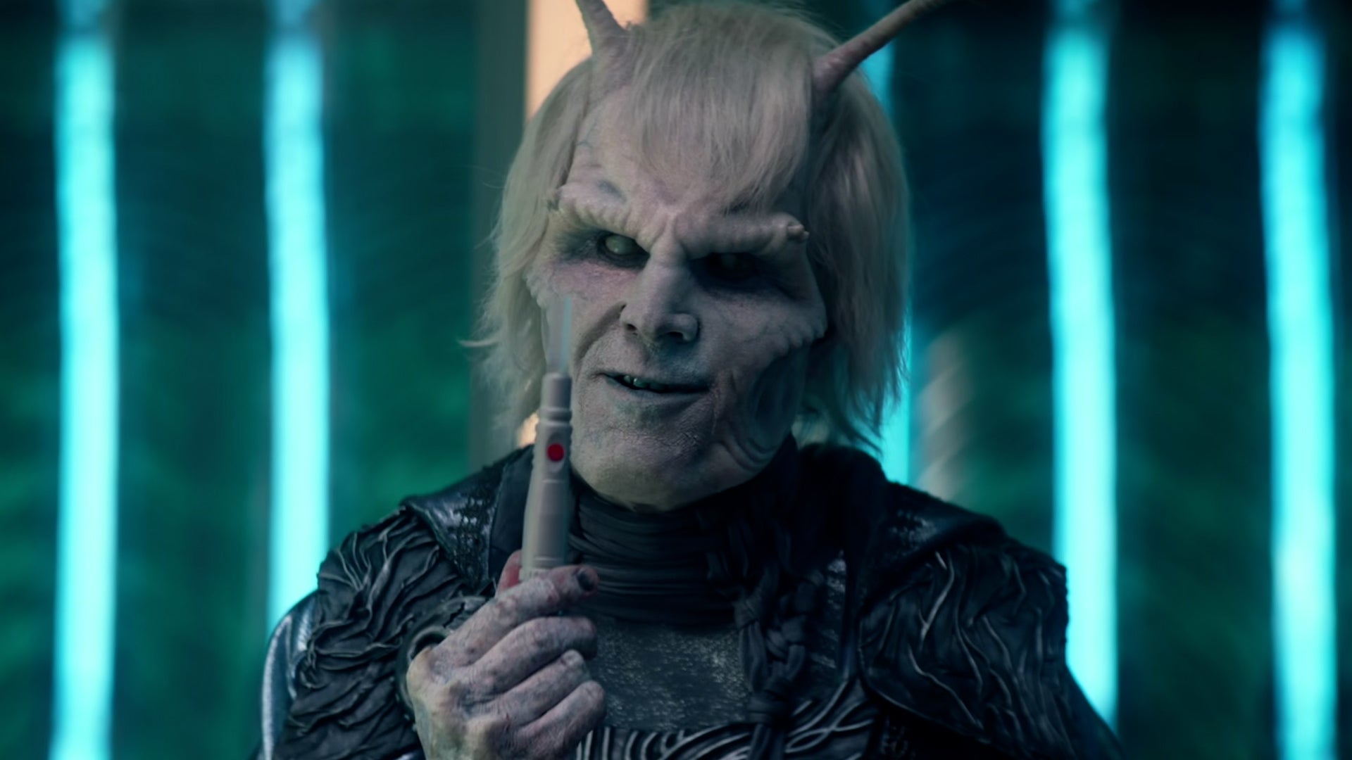 Hemmer (Bruce Horak) holds up a tool, smiling slightly.