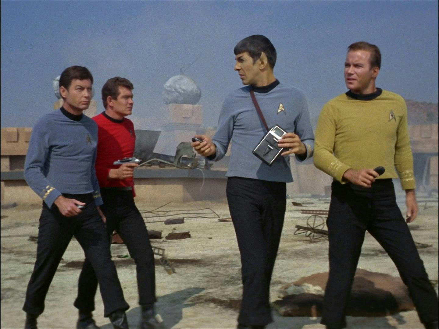 Kirk, Spock, McCoy, and a redshirt wearing officer explore the planet's surface.