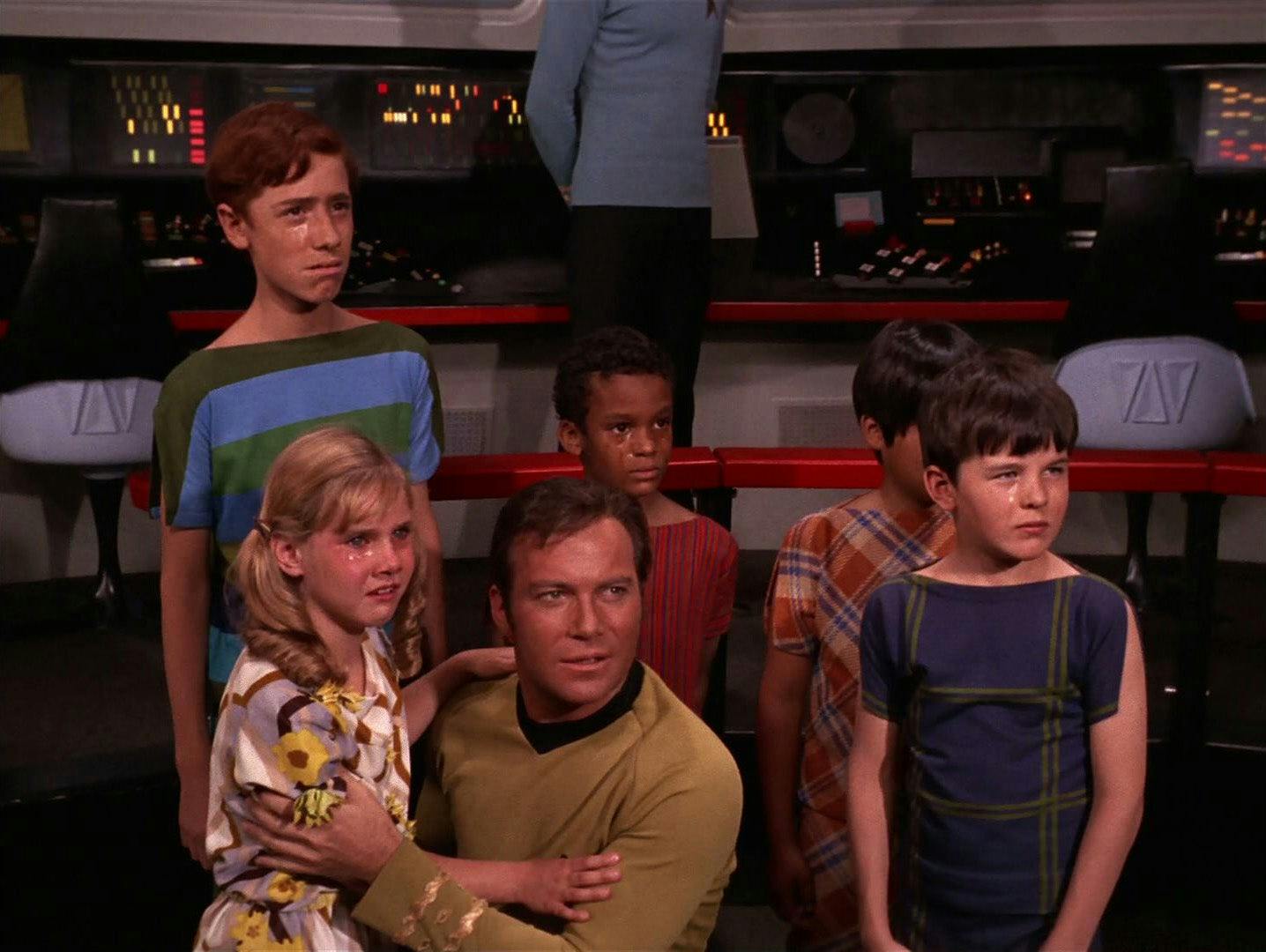 Aboard the Enterprise, a kneeling Kirk is surrounded by a group of tearful and scared children in 'And the Children Shall Lead'