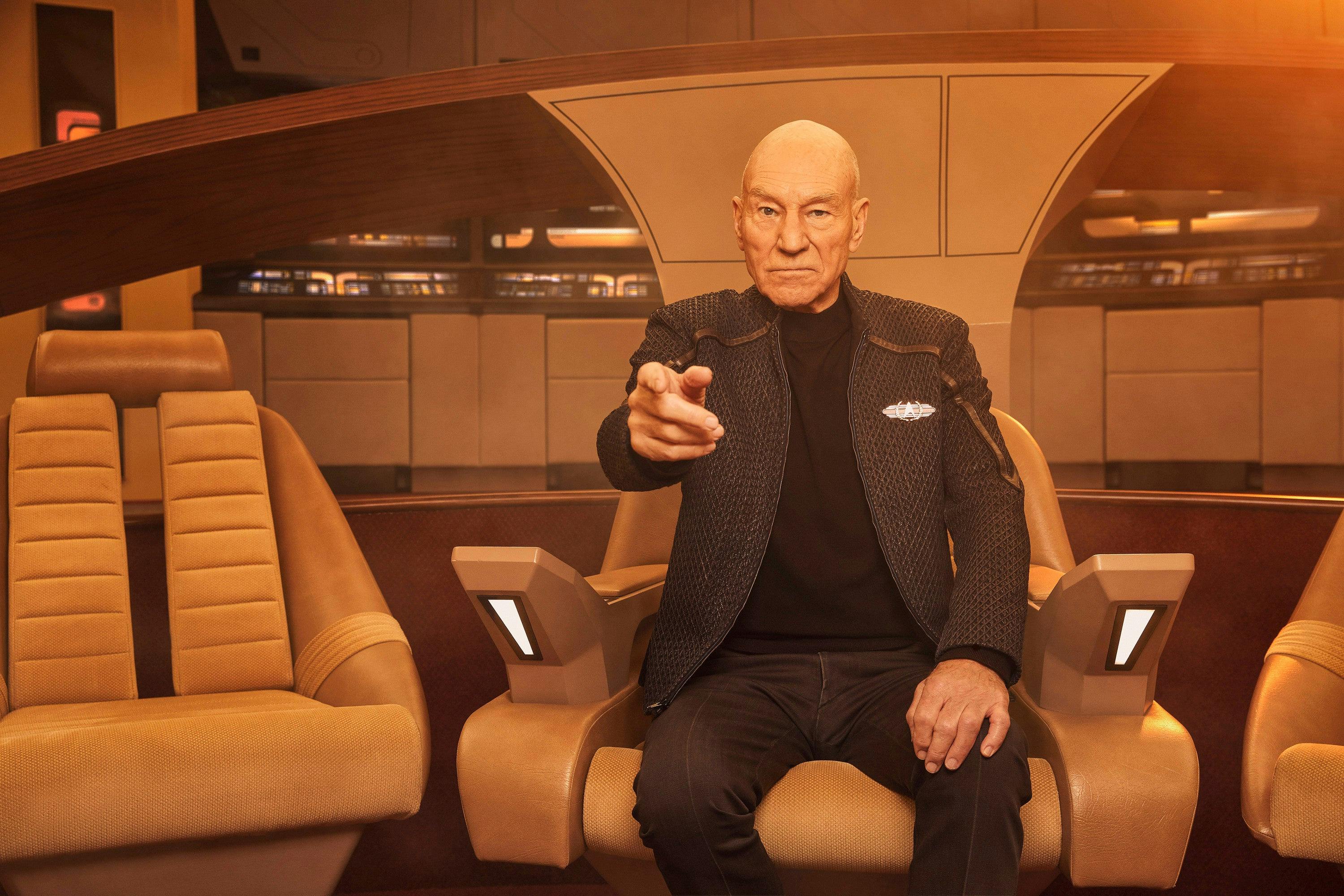 Jean-Luc Picard sitting in command on the Enterprise-D with his finger pointed forward signaling the helm to engage