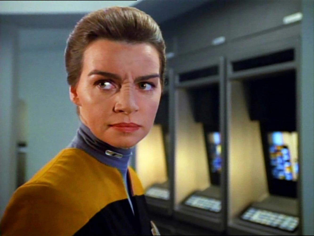 Seska, wearing a yellow Starfleet uniform, looks aorund.