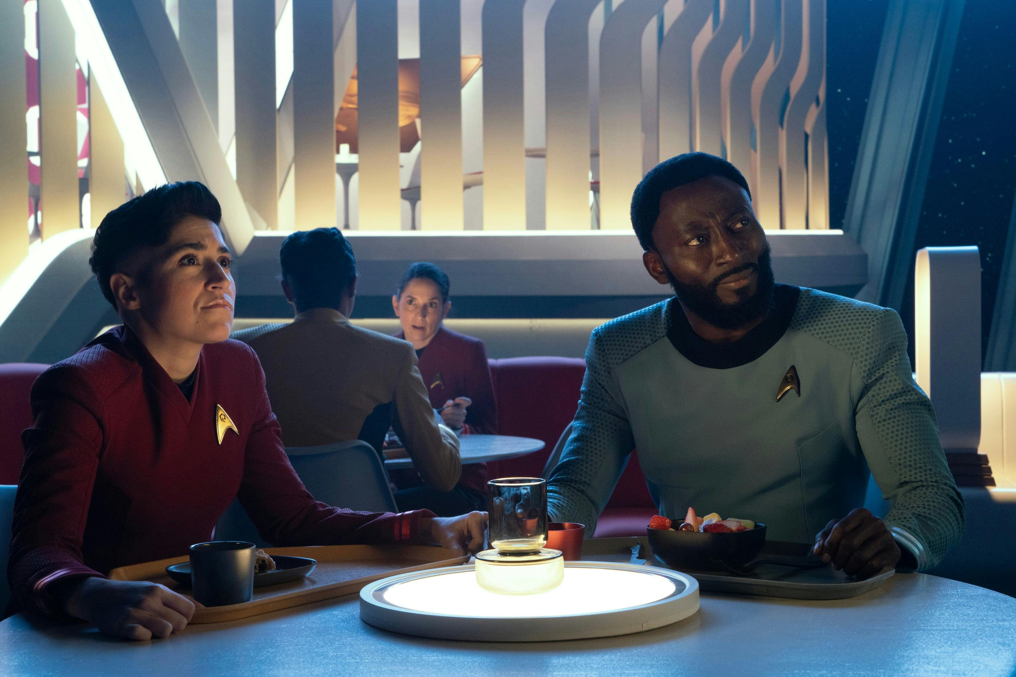 The seated Erica Ortegas and M'Benga look up from their table in the mess hall in 'Ad Astra per Aspera'