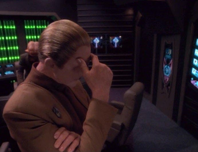 Odo rests his forehead in his hand as he's trapped in his office with Quark on Star Trek: Deep Space Nine