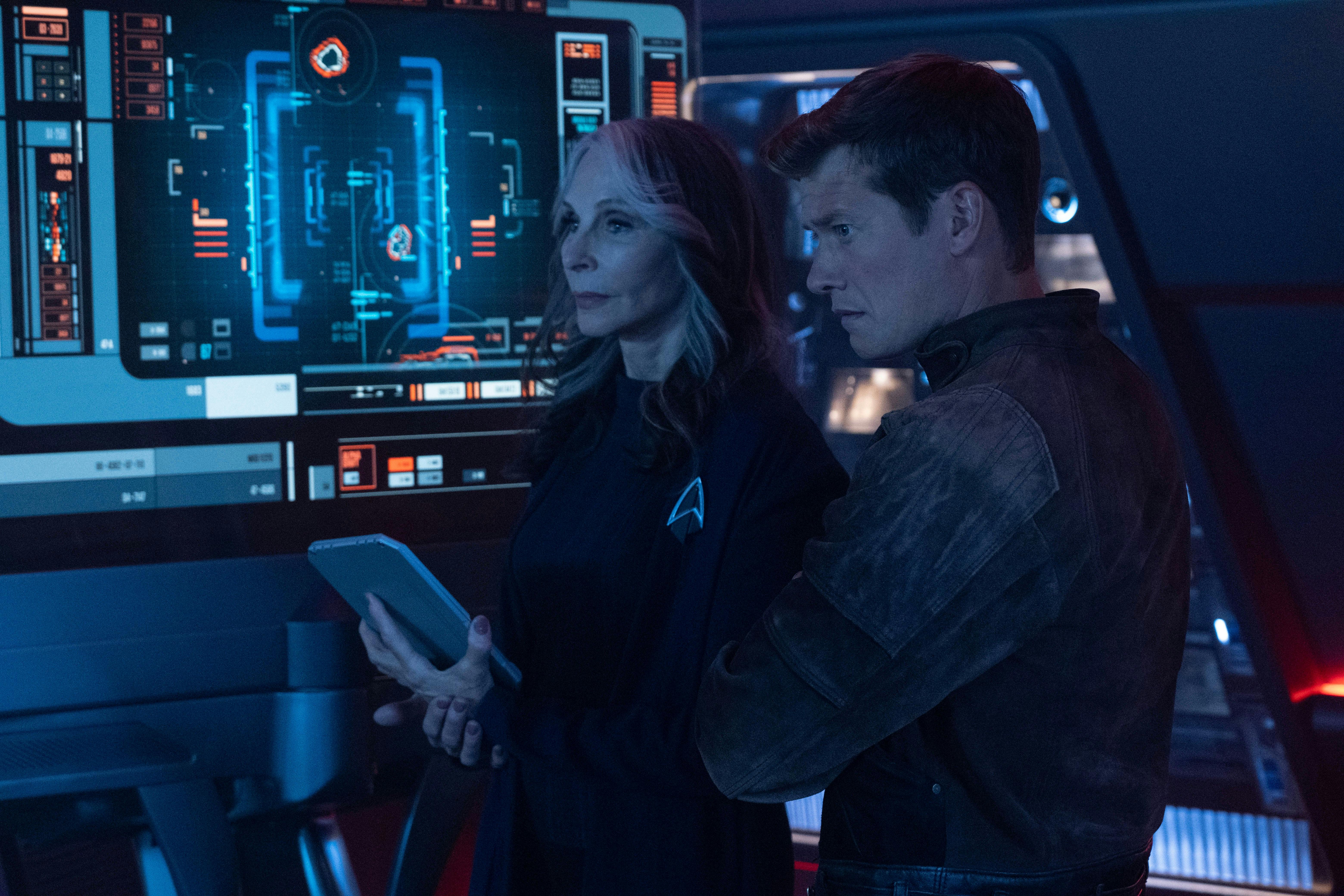 Beverly Crusher and Jack Crusher review data on her padd as well as the monitors ahead of them on the Titan bridge