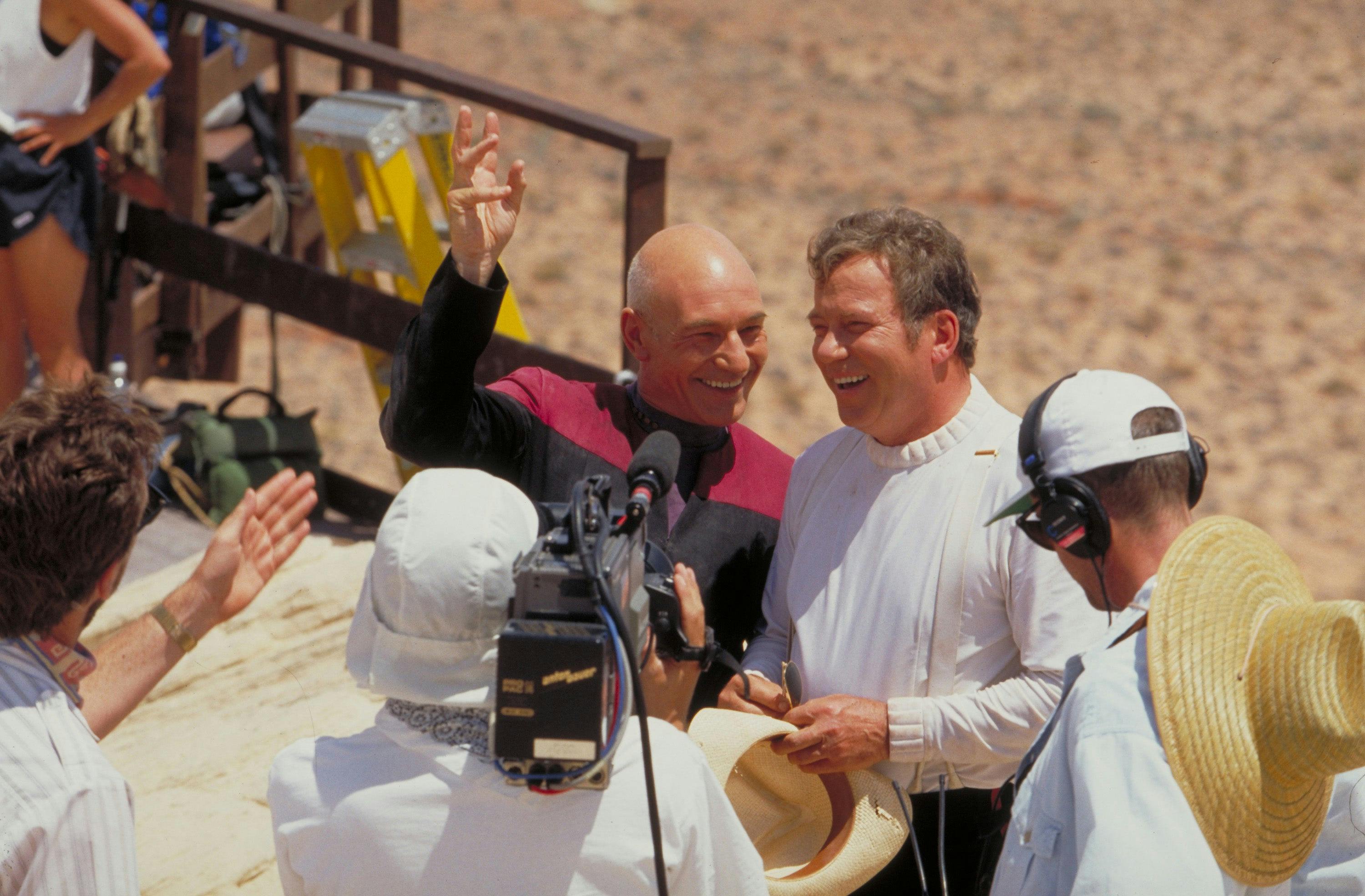 Patrick Stewart and William Shatner smiling on set of Star Trek Generations as camera crew capture the moment