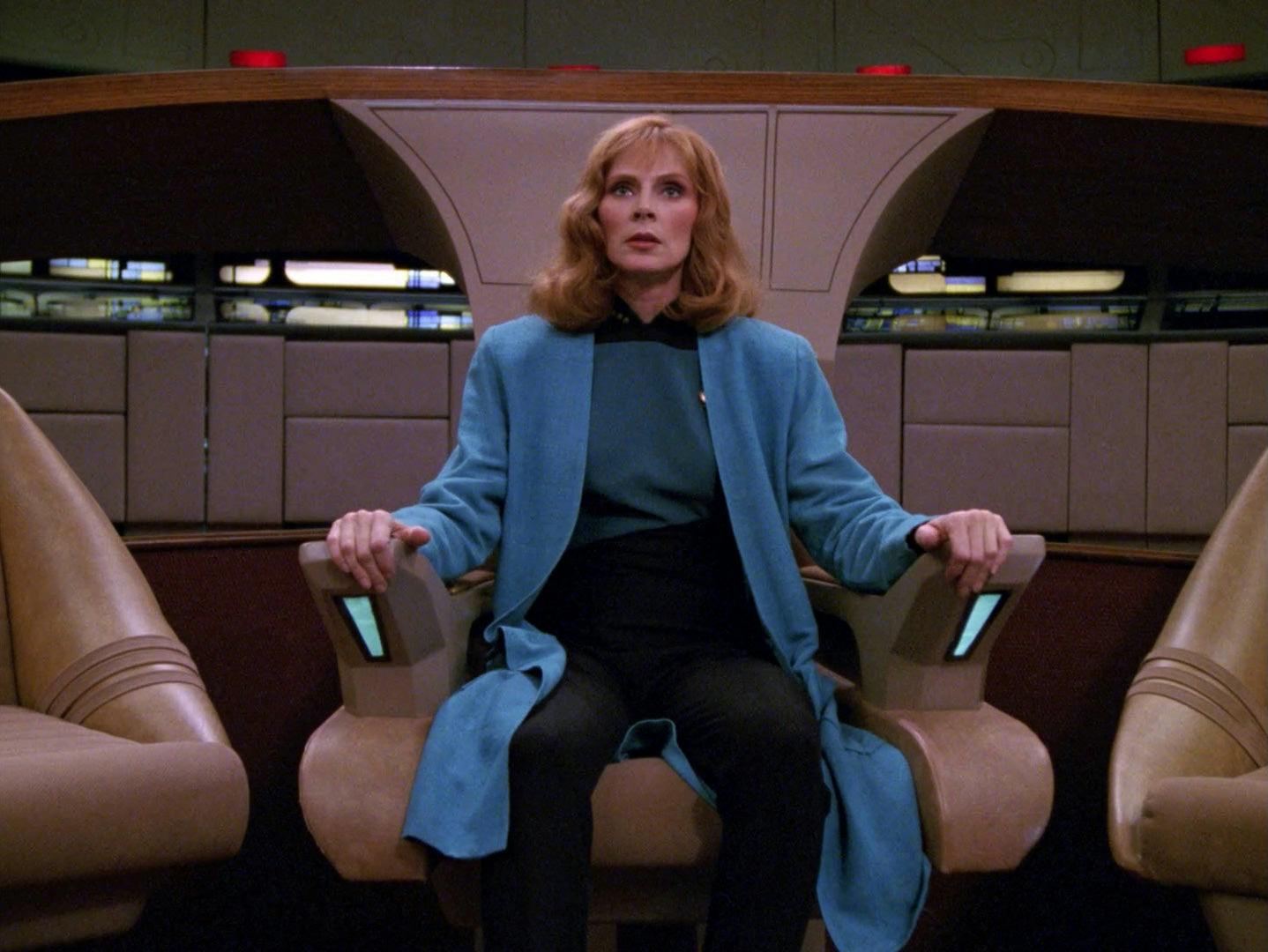 Beverly Crusher sits in the captain's chair on the Enterprise-D in 'Remember Me'