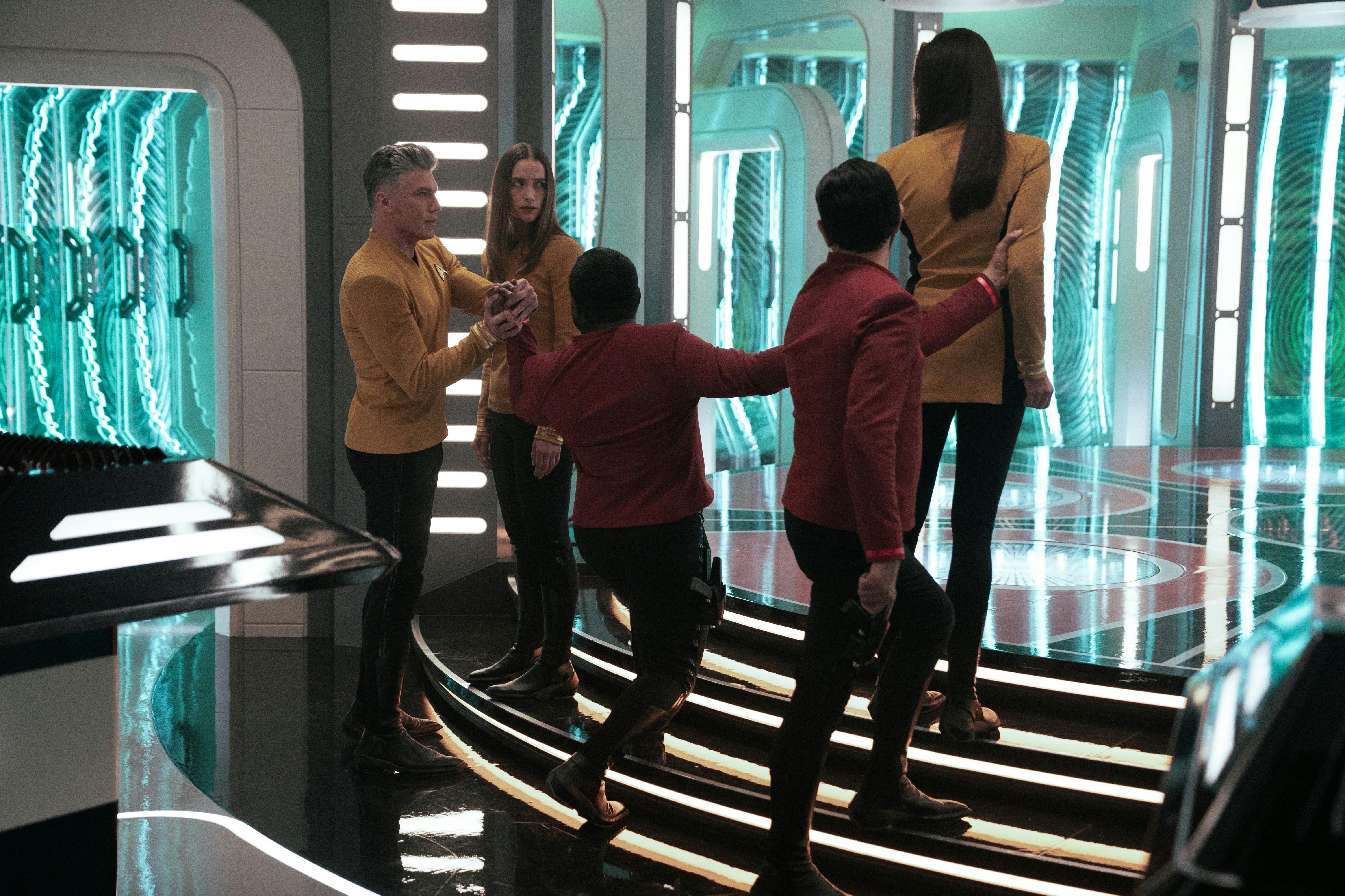 Captain Pike (Anson Mount) tries to intervene when Number One (Rebecca Romijn) is arrested by two security officers.