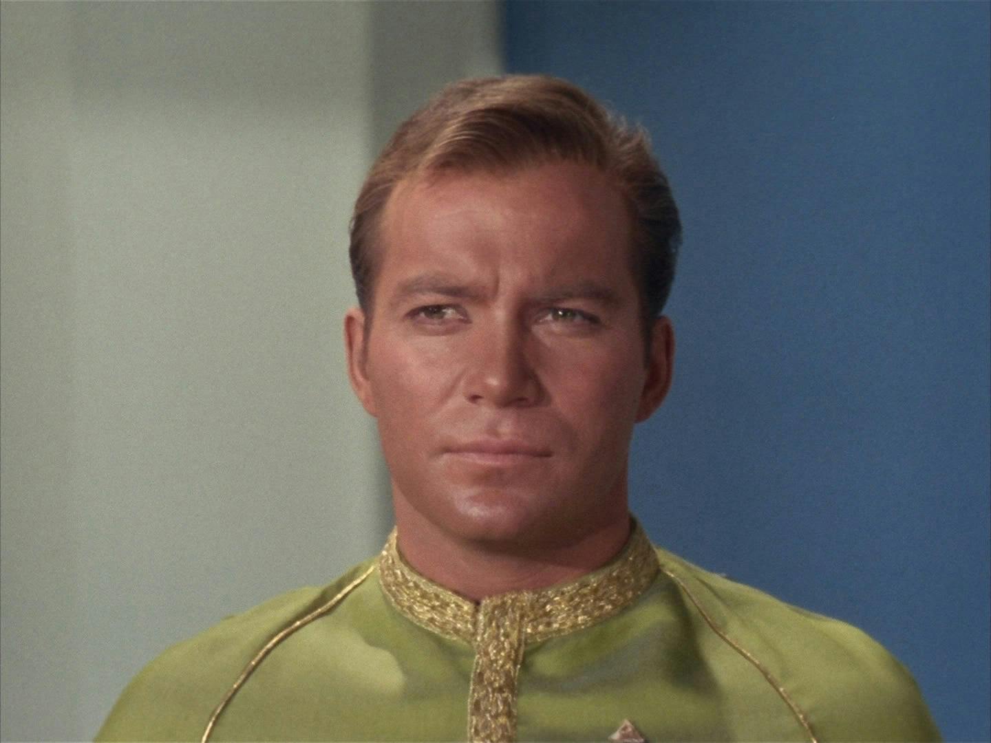 Captain Kirk, wearing his dress uniform, stands at attention. 