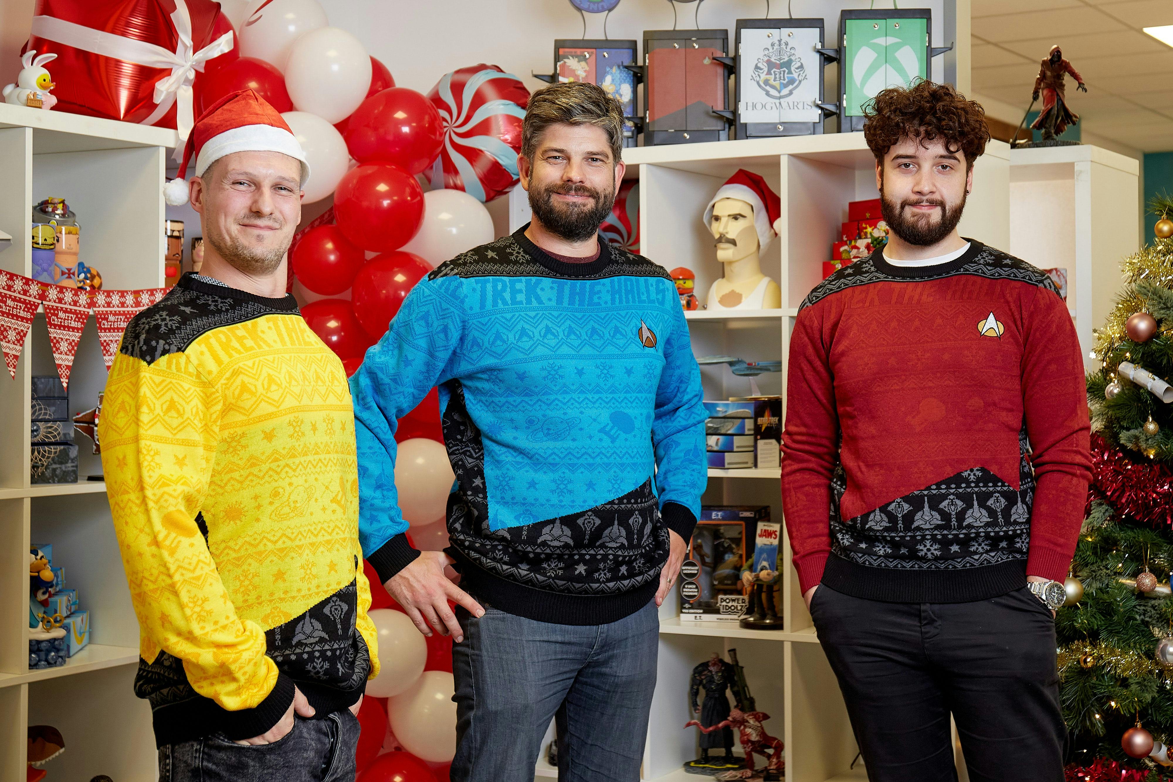 Three lads wearing the Numskull Star Trek 'Trek the Halls' Ugly Sweater Jumpers in an office