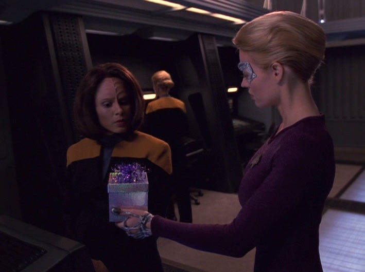 B'Elanna Torres looks at a gift that Seven of Nine holds a gift in her hands on Star Trek: Voyager
