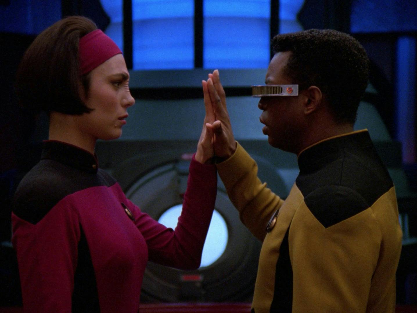 Ensign Ro Laren and Geordi La Forge stand directly in front of each other with their hands lifted and palms touching in 'The Next Phase'