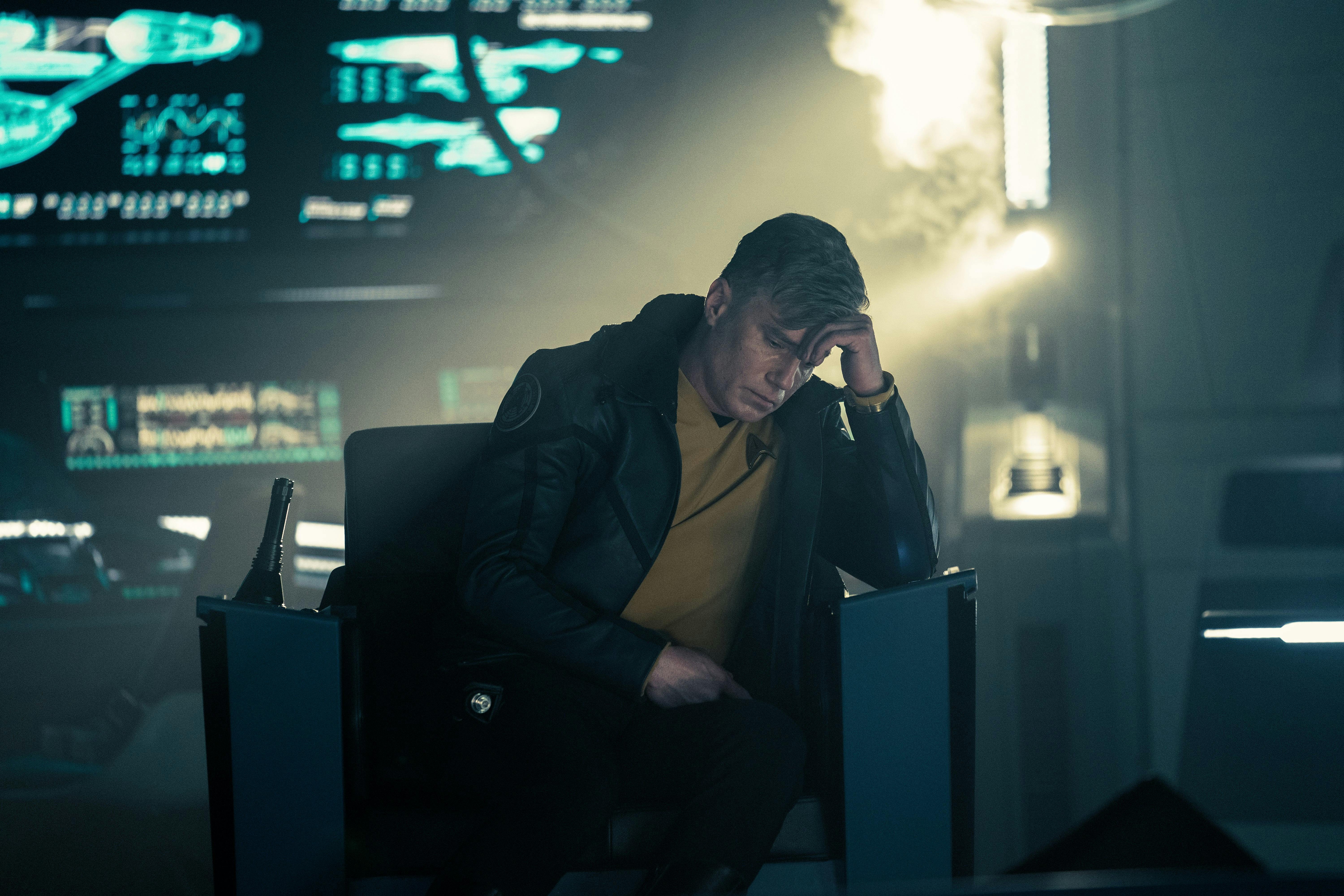 Captain Pike (Anson Mount) sits slumped over in a captain's chair. He is wearing a jacket over his uniform.