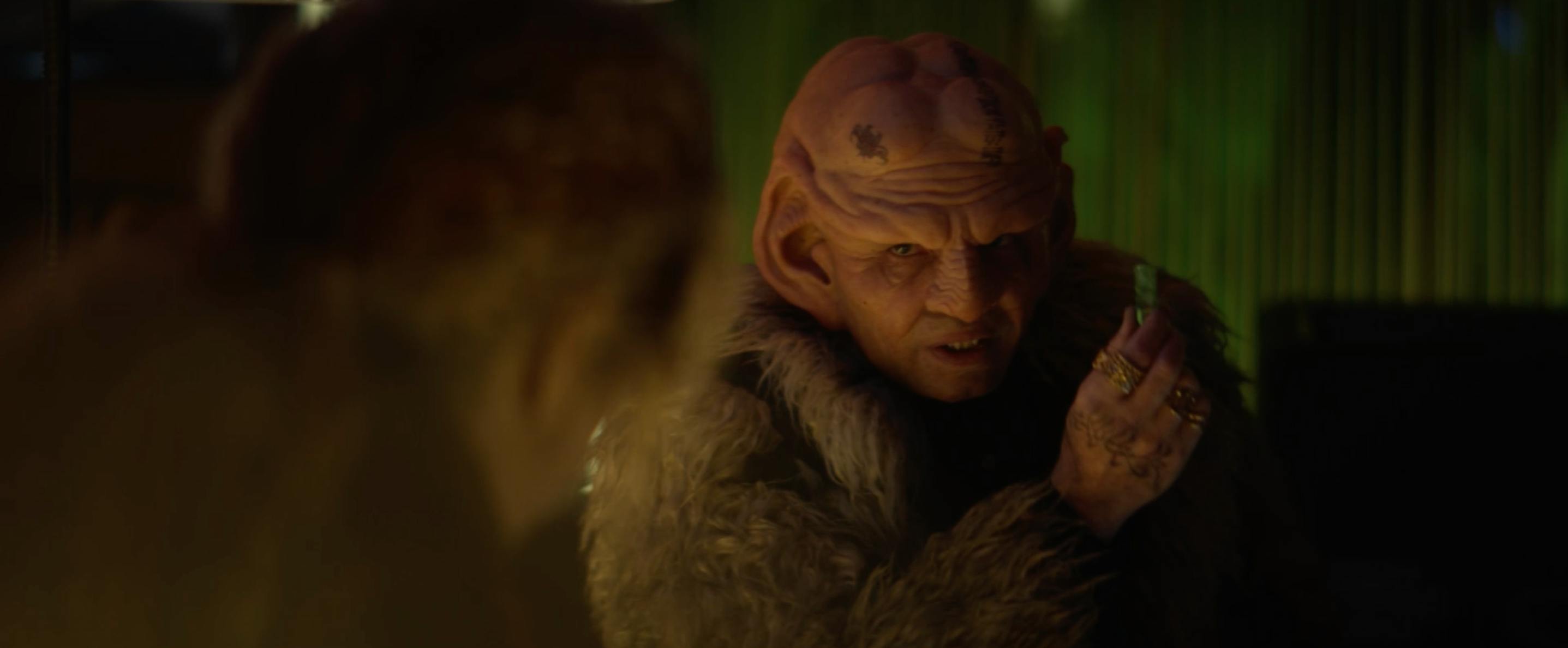 Sneed the Ferengi broker holds a vial of Splinter in front of Raffi in District Six in Star Trek: Picard
