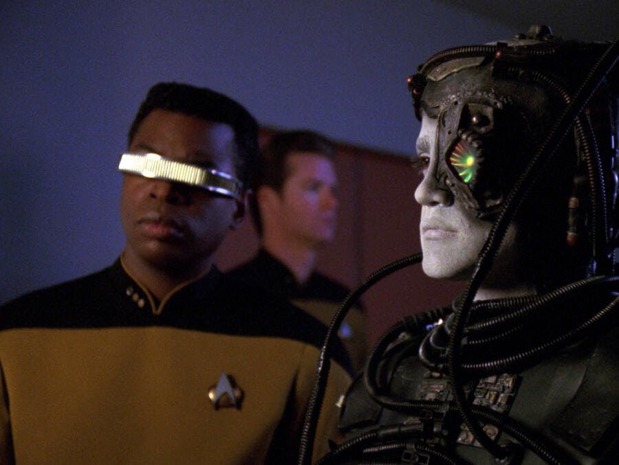 Geordi and the Borg drone Hugh stand side-by-side, with an officer stationed behind them, in 'I, Borg'