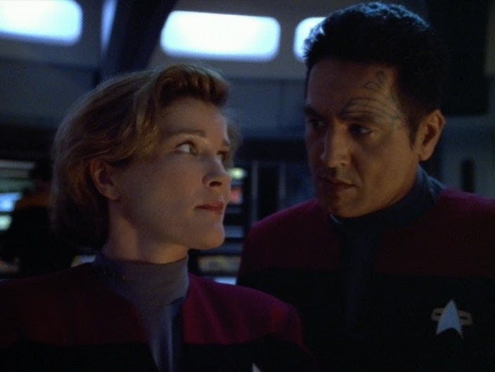 Janeway looks at Chakotay as they stand on the bridge in 'Year of Hell, Part I'