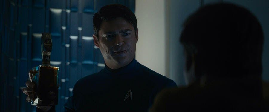 Assessing Kirk's melancholy, Leonard Bones McCoy holds up a bottle of whiskey to lift his friend's spirit in Star Trek Beyond