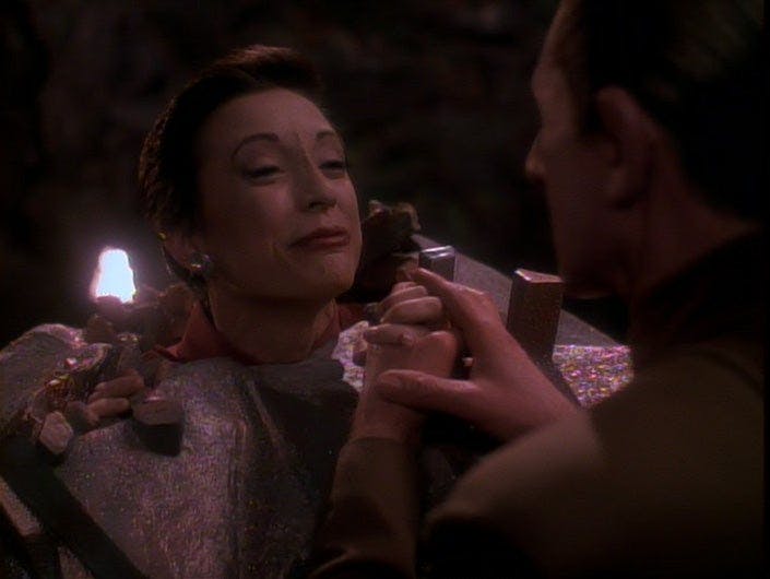 Fake Kira trapped in a rock formation grips Odo's hand in 'Heart of Stone'