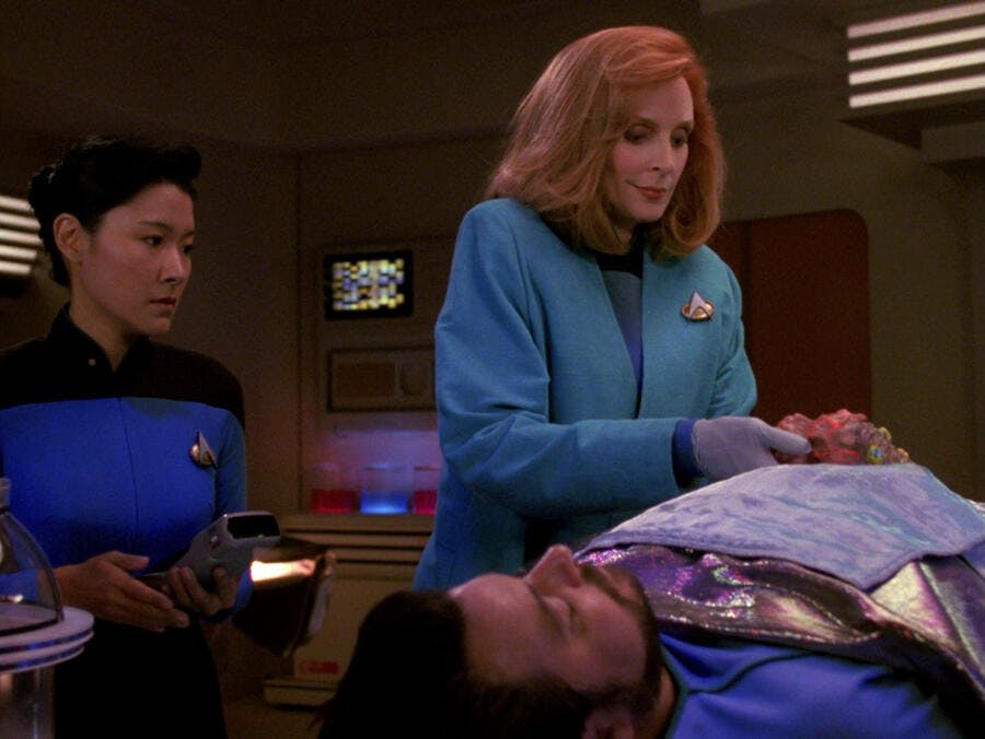 Nurse Alyssa Ogawa watches as Dr. Beverly Crusher implants a Trill symbiont into William Riker in 'The Host'