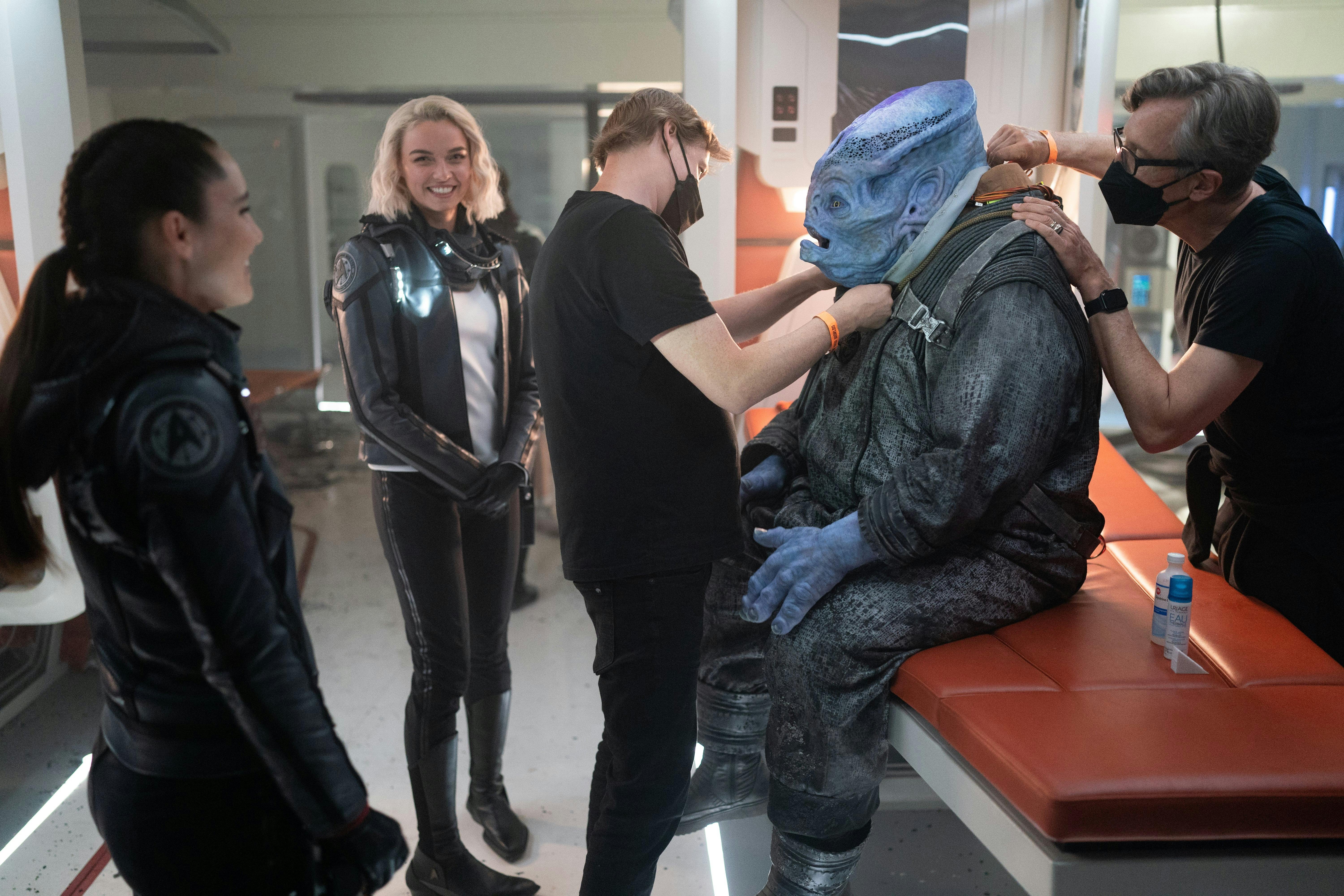 Jess Bush and Christina Chong laugh as the crew gets ready to film a scene with a blue alien.