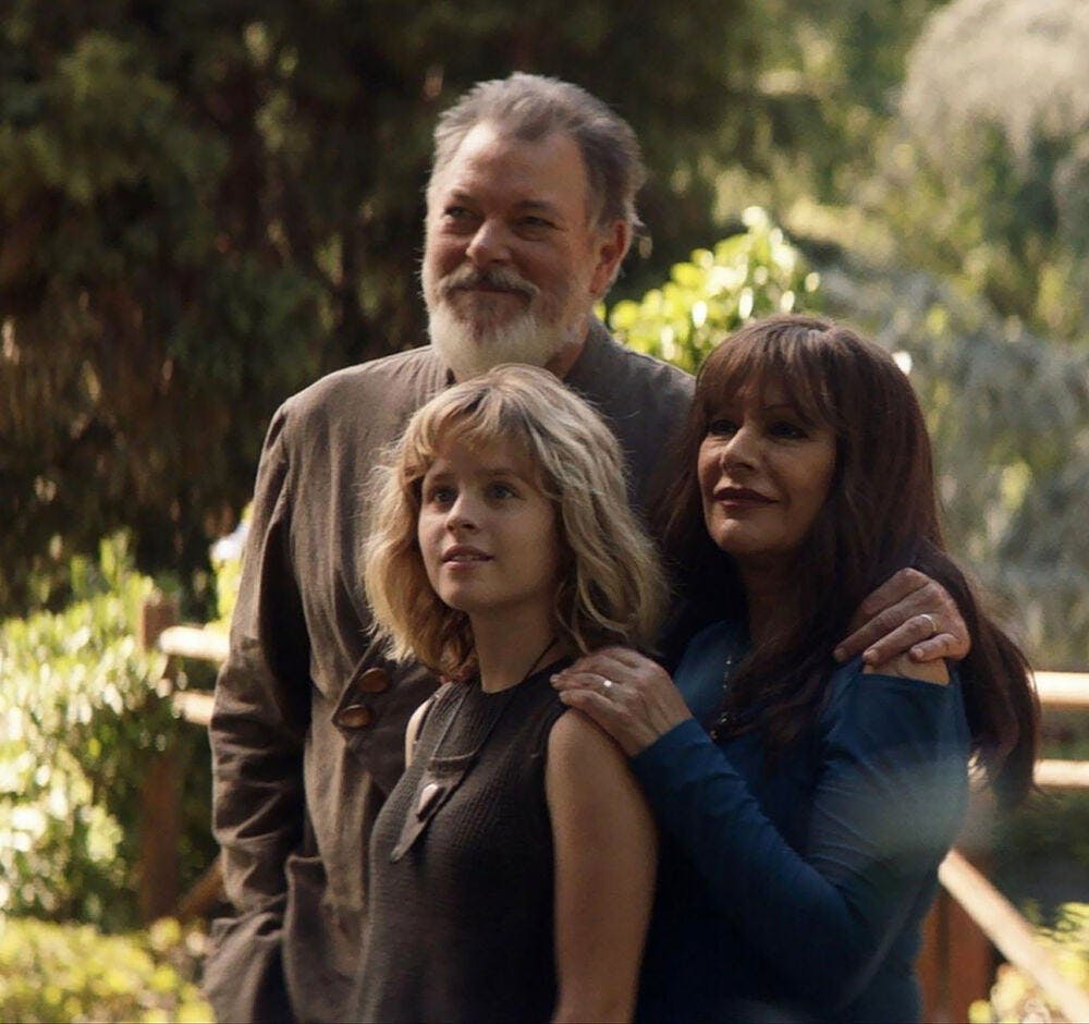 In front of their home, Riker, Deanna Troi, and their daughter warmly greet Picard in 'Nepenthe'