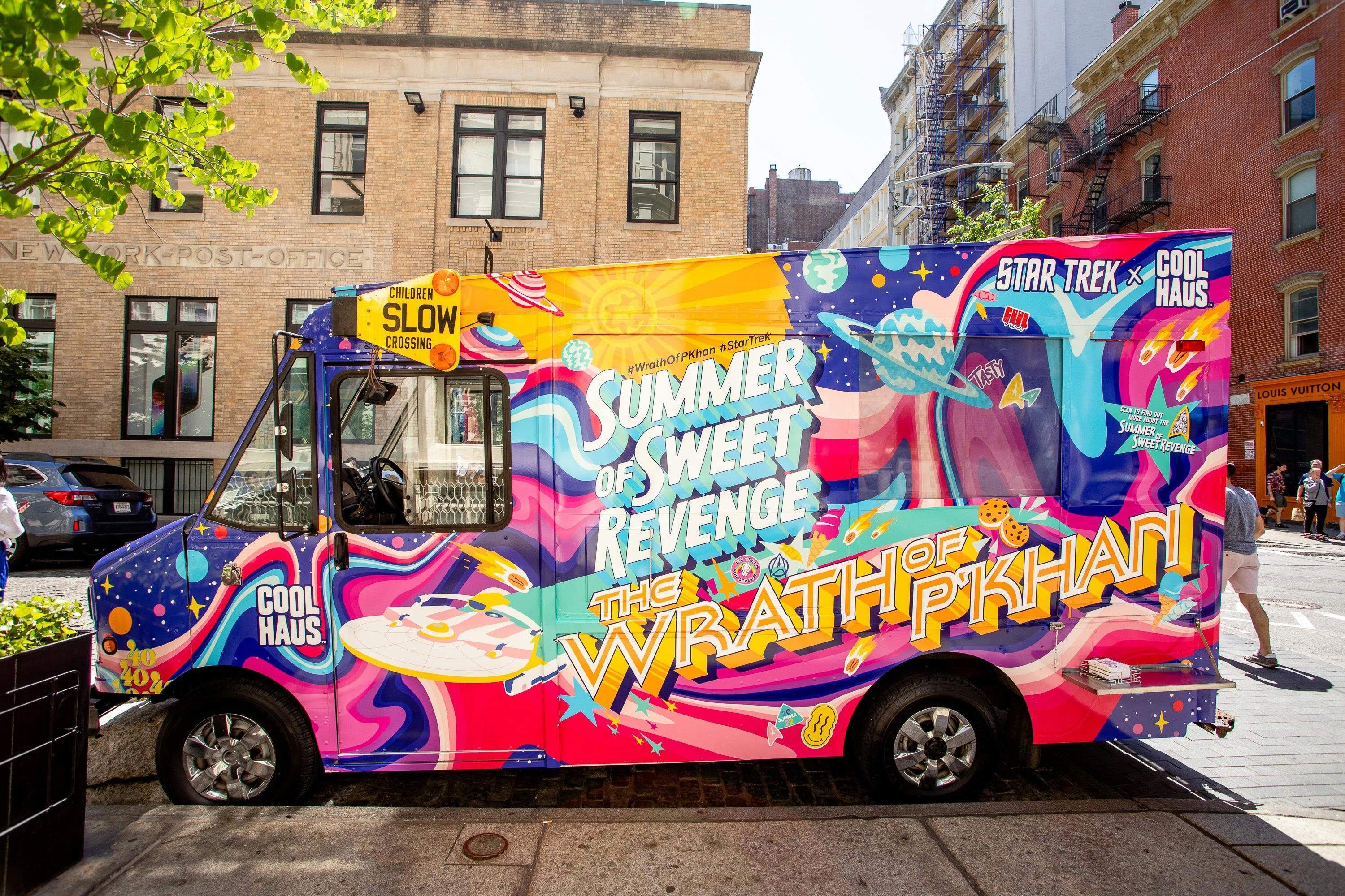 The truck is parked along a street. You can see "The Summer of Sweet Revenge" and "The Wrath of P'Khan" written on it in bright colors against a psychedelic background