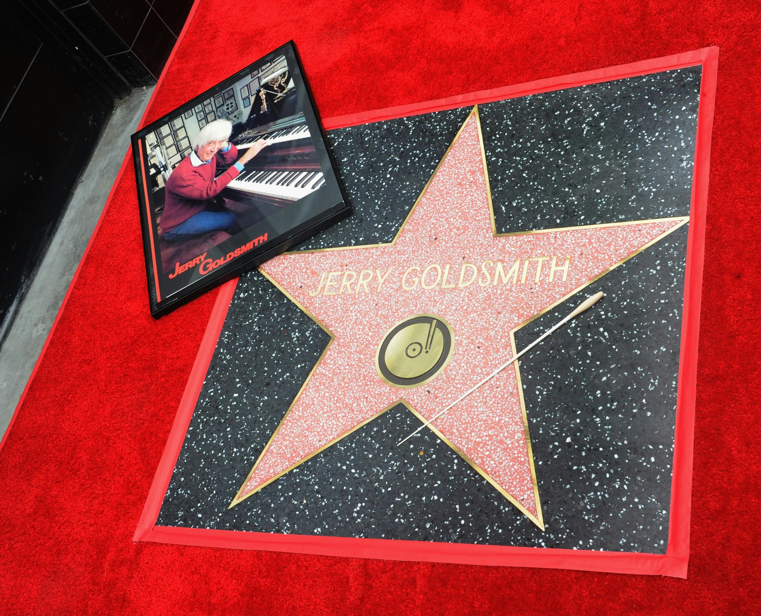Close-up of Jerry Goldsmith's Hollywood Walk of Fame star along with a framed image of the composer at his piano along with a conductor's baton resting on the star