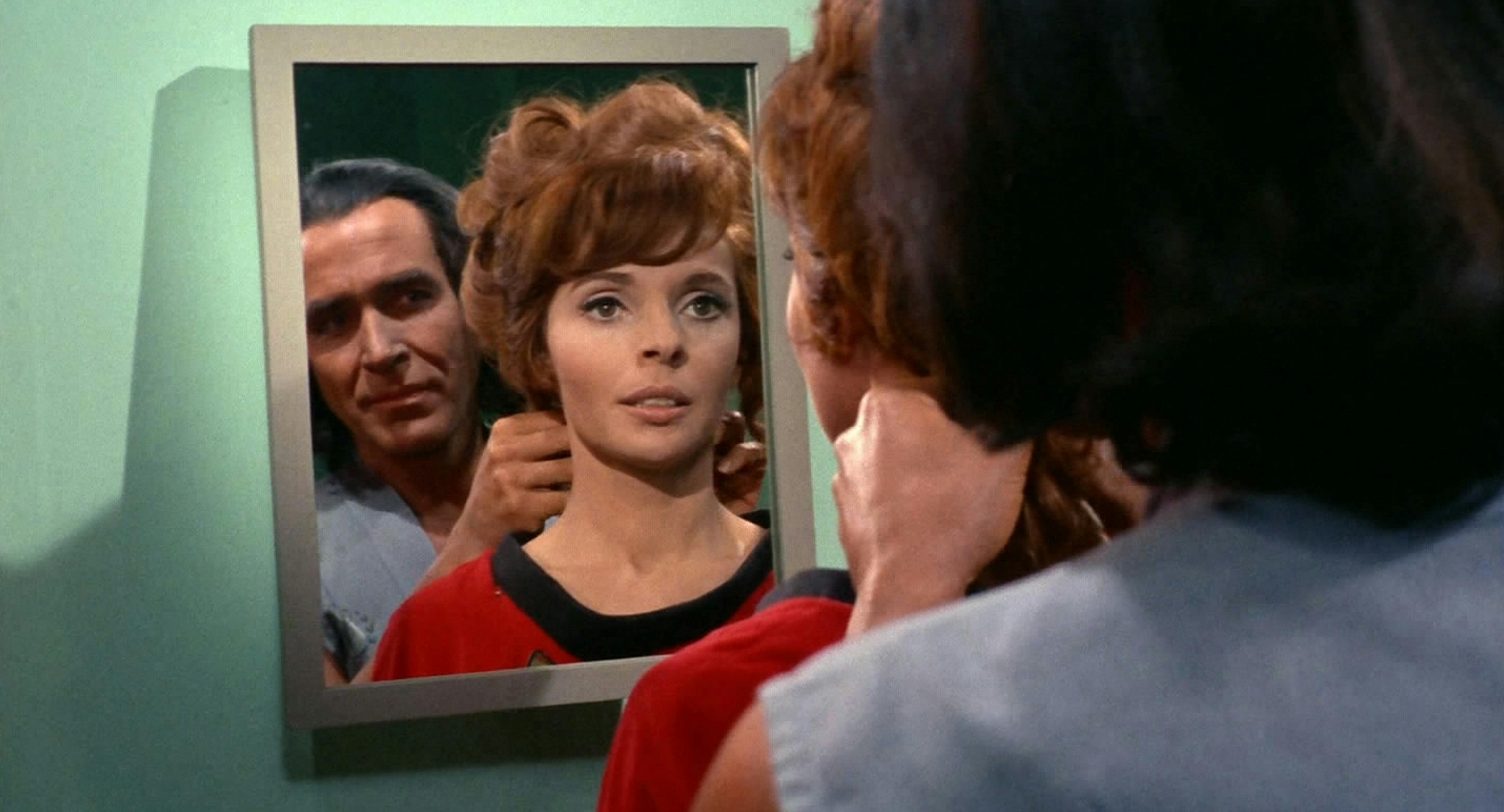 Khan stands behind Marla McGivers as they look at their reflection in the mirror on Space Seed