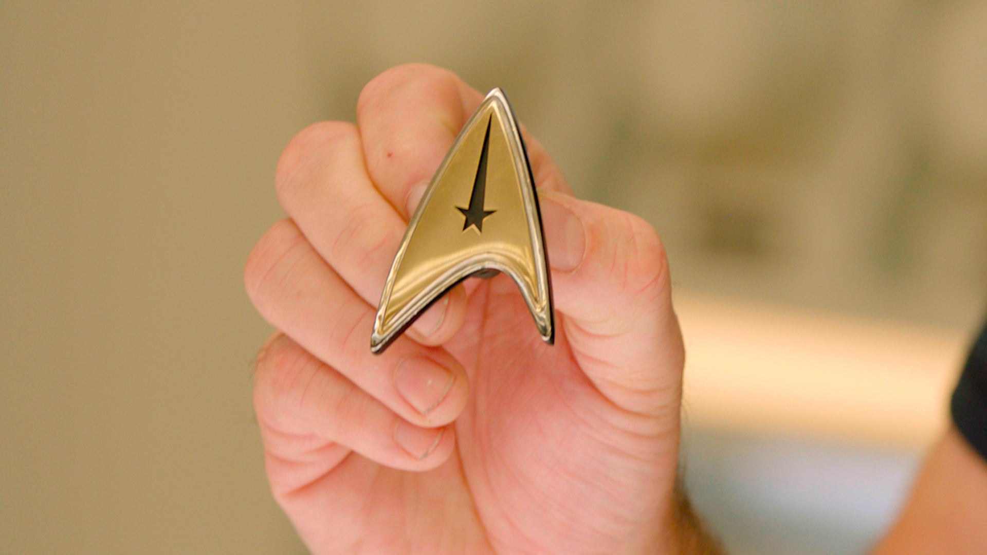 Hand holding the Strange New Worlds delta pin