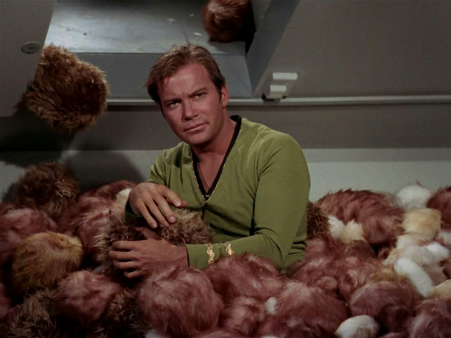 An unhappy Captain Kirk stands in a pile of tribbles that's up to his waist as more fall from above in 'The Trouble with Tribbles'