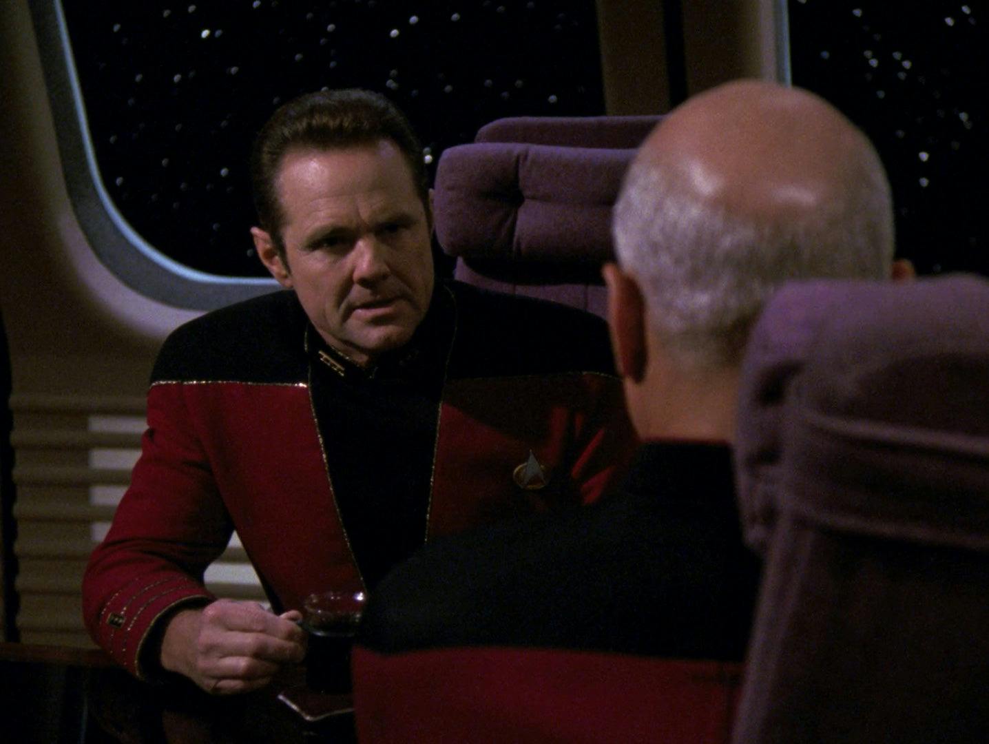 Kennelly sits across from Picard in a defensive and patronizing pose in the observation dock of The Next Generation's Enisgn Ro