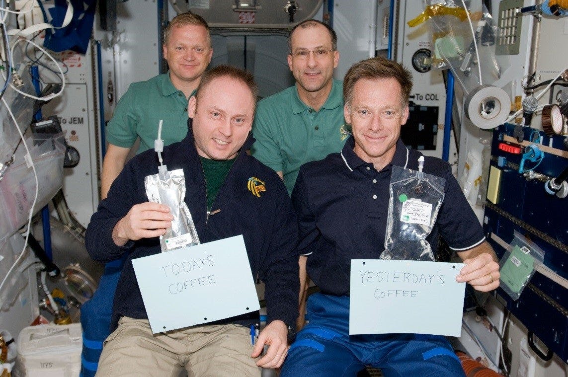 (L-R) Crew members Michael Finke and Chris Ferguson, Eric Boe, and Donald Pettit show off the former coffee bags in 2008.