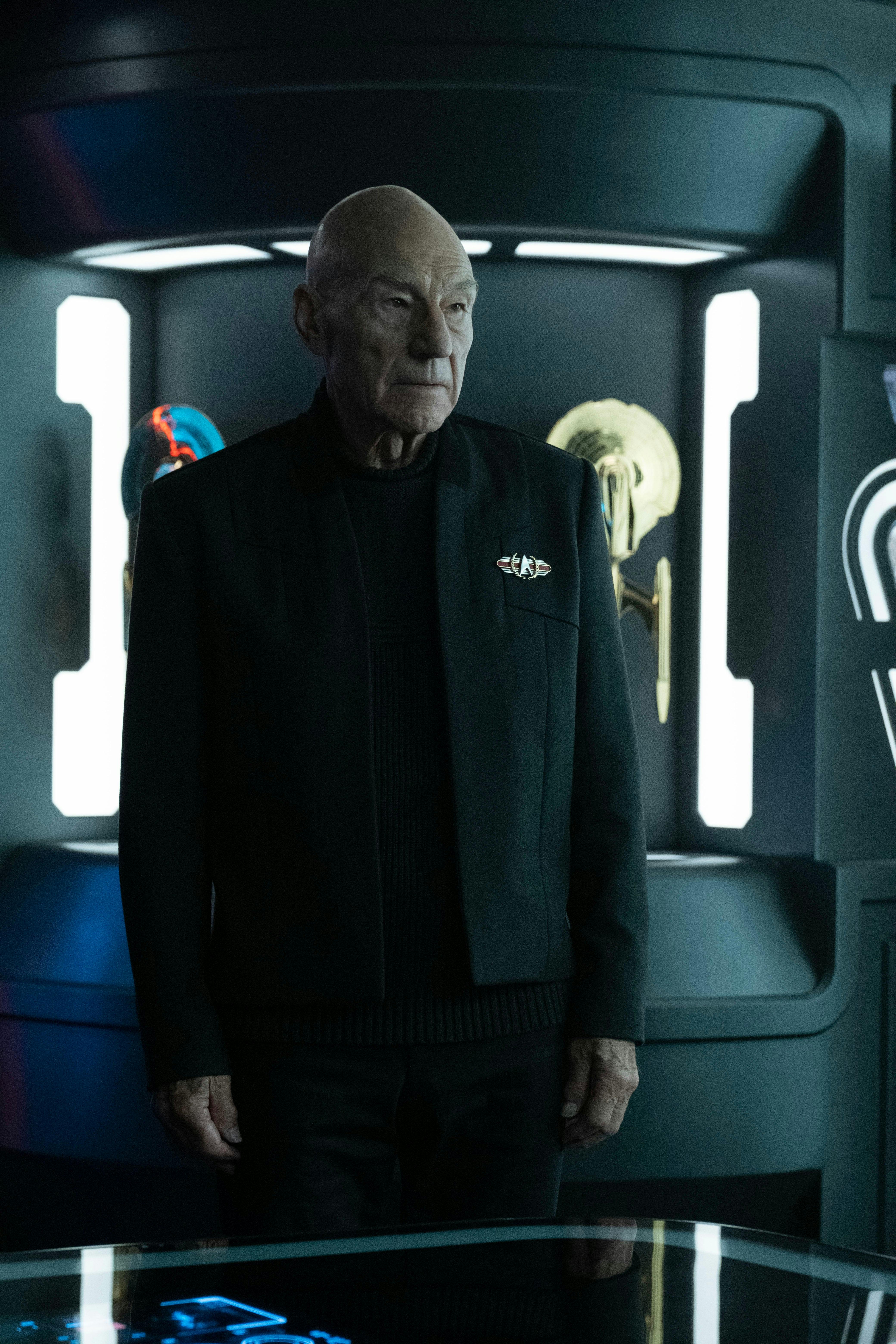 Admiral Jean-Luc Picard stands in front of a display of artifacts on Star Trek: Picard
