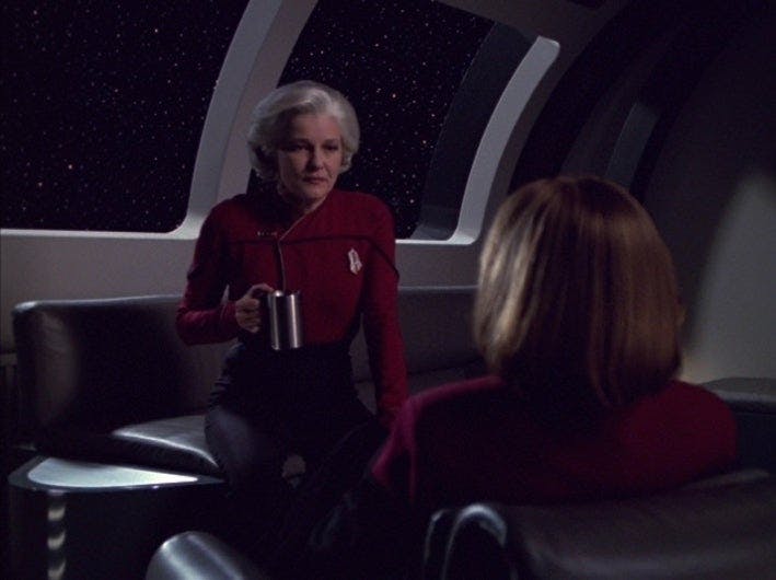 Future Admiral Janeway faces the younger Captain Janeway with her coffee in hand in 'Endgame'