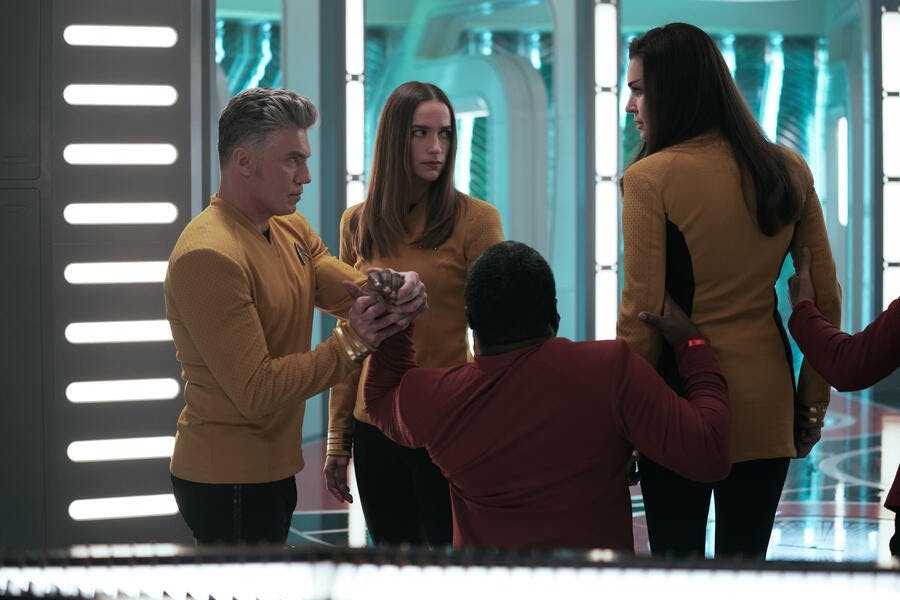 Captain Pike (Anson Mount) tries to stop two security officers and Captain Batel from arresting Number One (Rebecca Romijn).