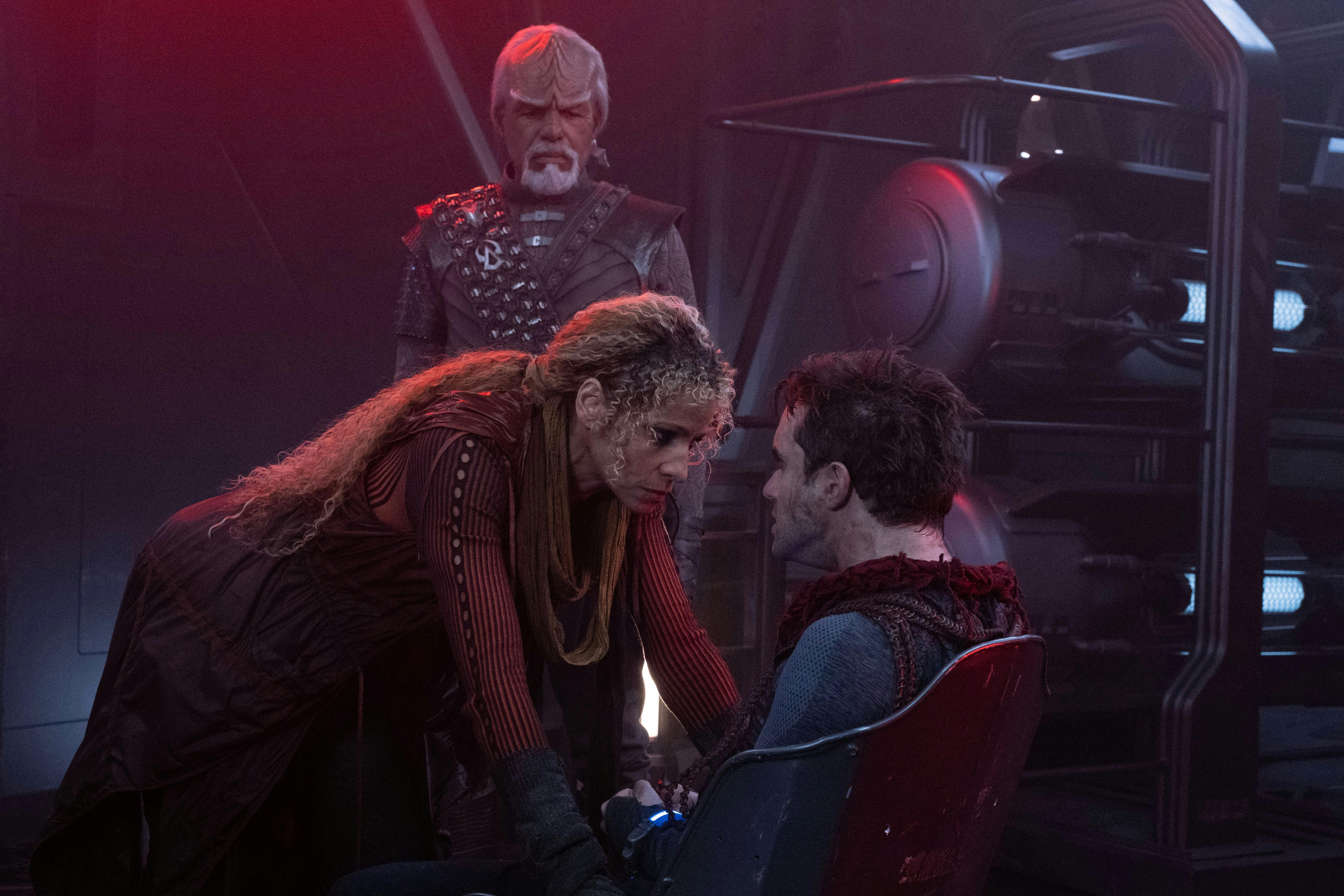 Raffi interrogates Titus Rikka as Worf looks on over her shoulder on Star Trek: Picard 