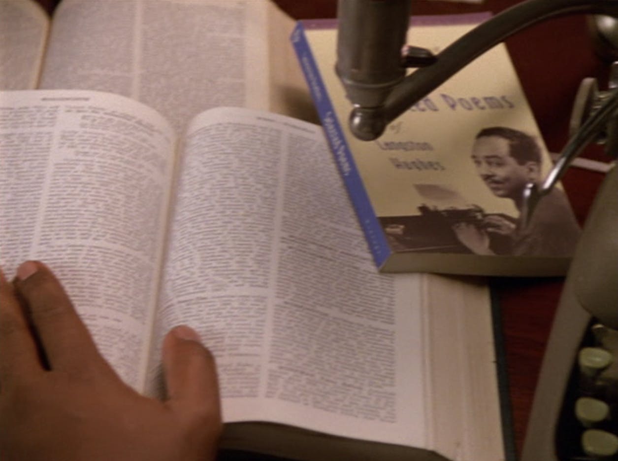 Benny Russell (Sisko) leafs through several open books on his desk, which includes Langston Hughes' collection of poems, in 'Far Beyond the Stars'