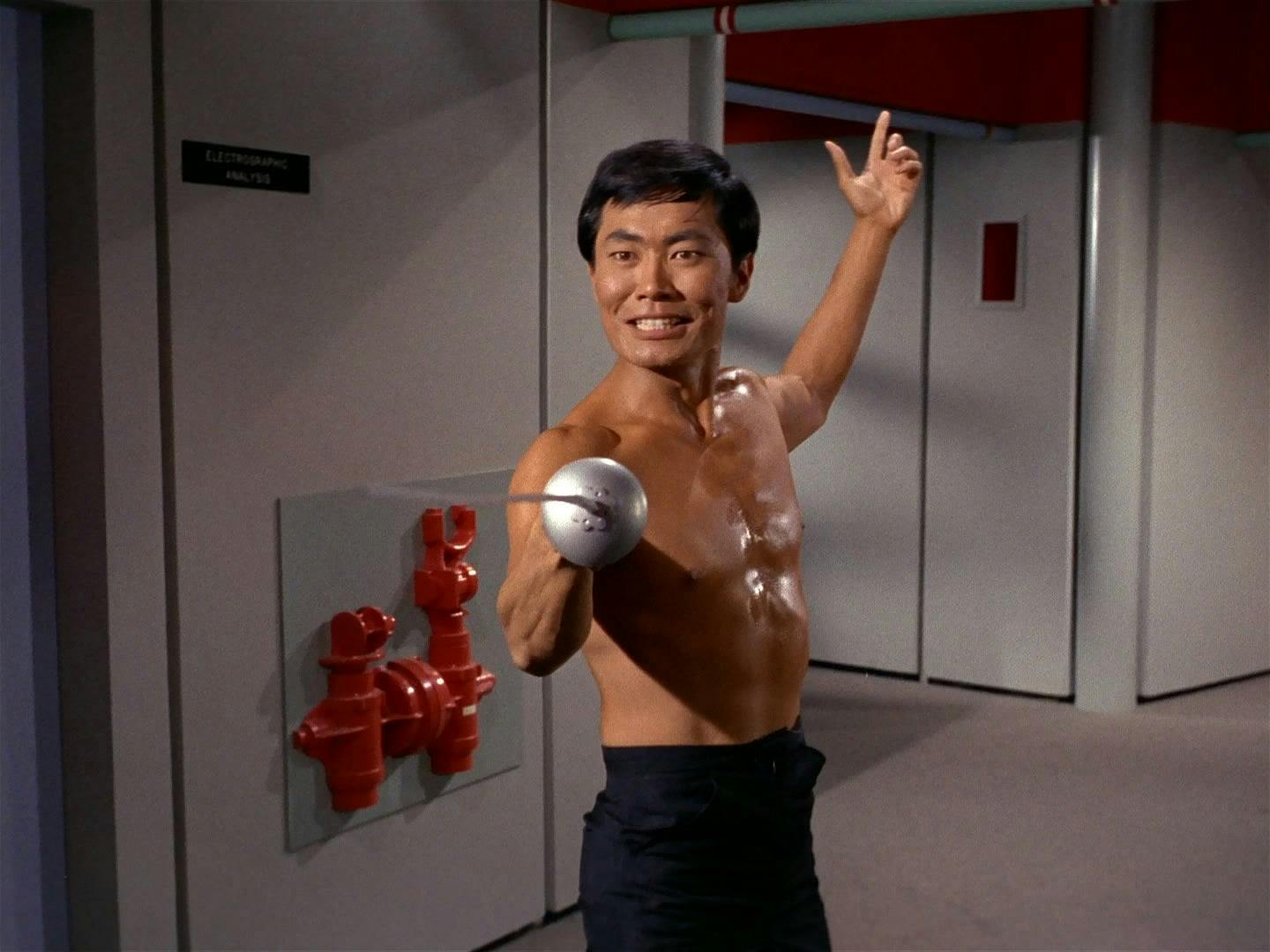 Sulu holds a fencing lancet while standing shirtless in the corridor of the Enterprise in 'The Naked Time'