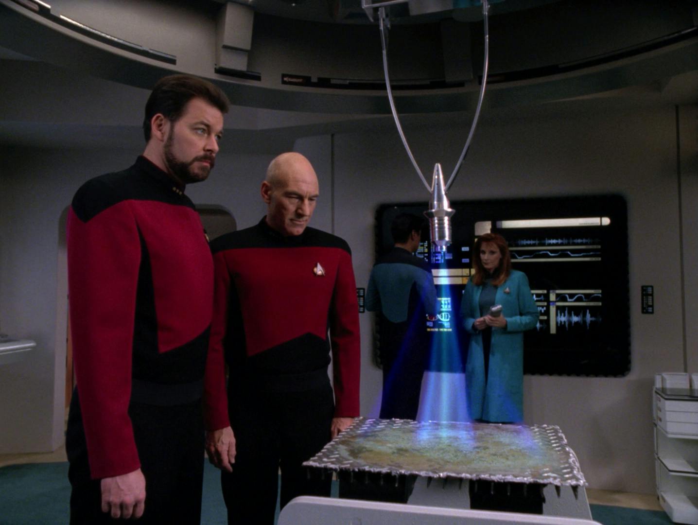 Riker and Captain Picard observe Dr. Crusher's analysis of a potential coalescent lifeform in 'Aquiel'