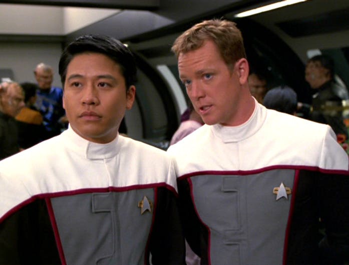 Harry Kim and Tom Paris wearing Delta Flyer racing uniforms stand side by side in 'Drive'