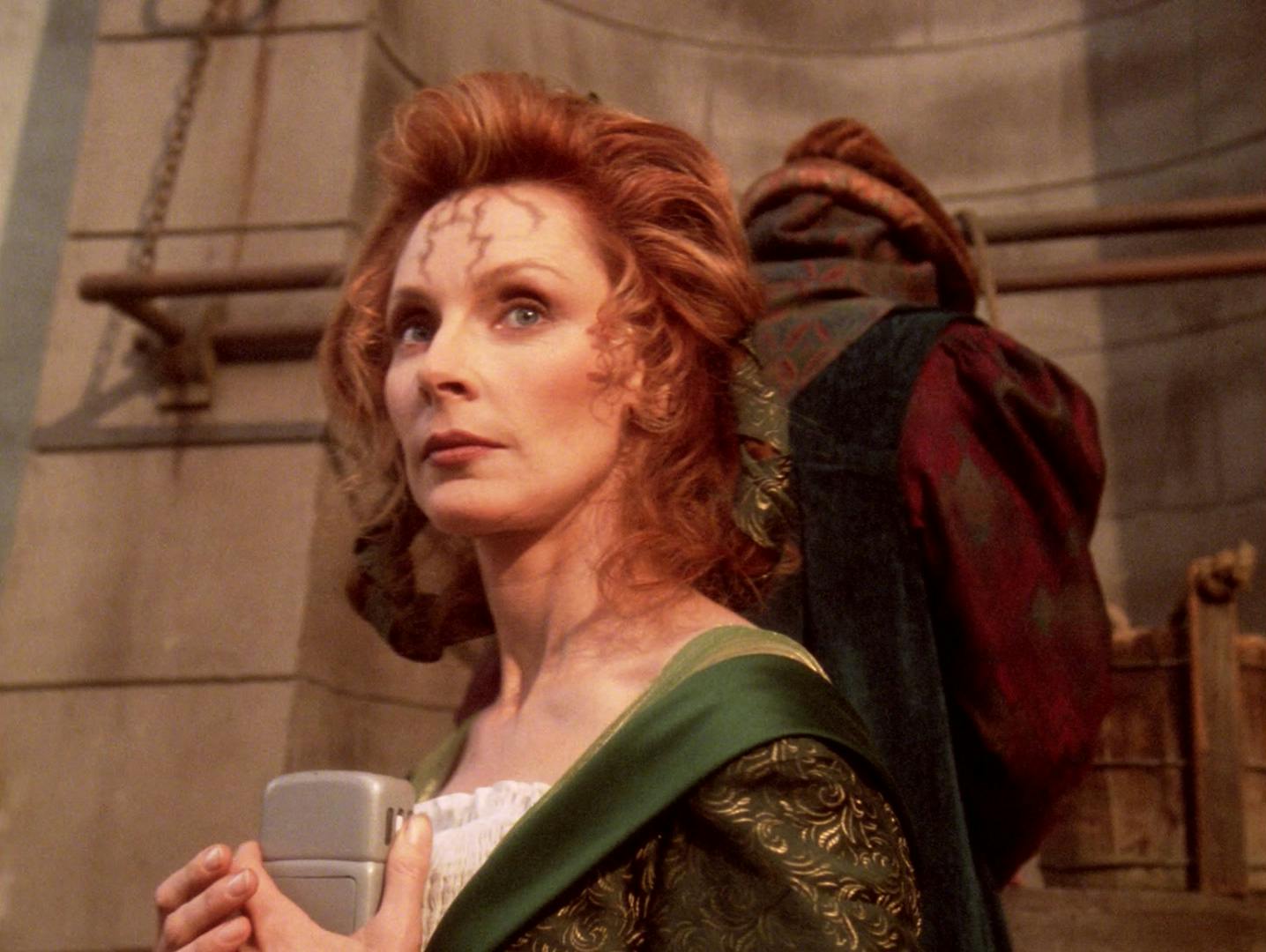 Dr. Crusher, disguised as a Barkonian, clutches her tricorder to her chest as she searches for Data on Barkon IV in 'Thine Own Self'