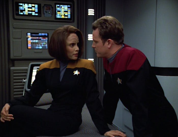 Seated on a medbed facing away, B'Elanna Torres turns around to face Tom Paris who leans towards her in 'Revulsion'