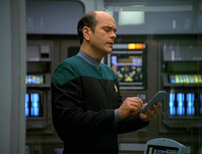 The Doctor holds his tricorder while in Sickbay in 'The Swarm'