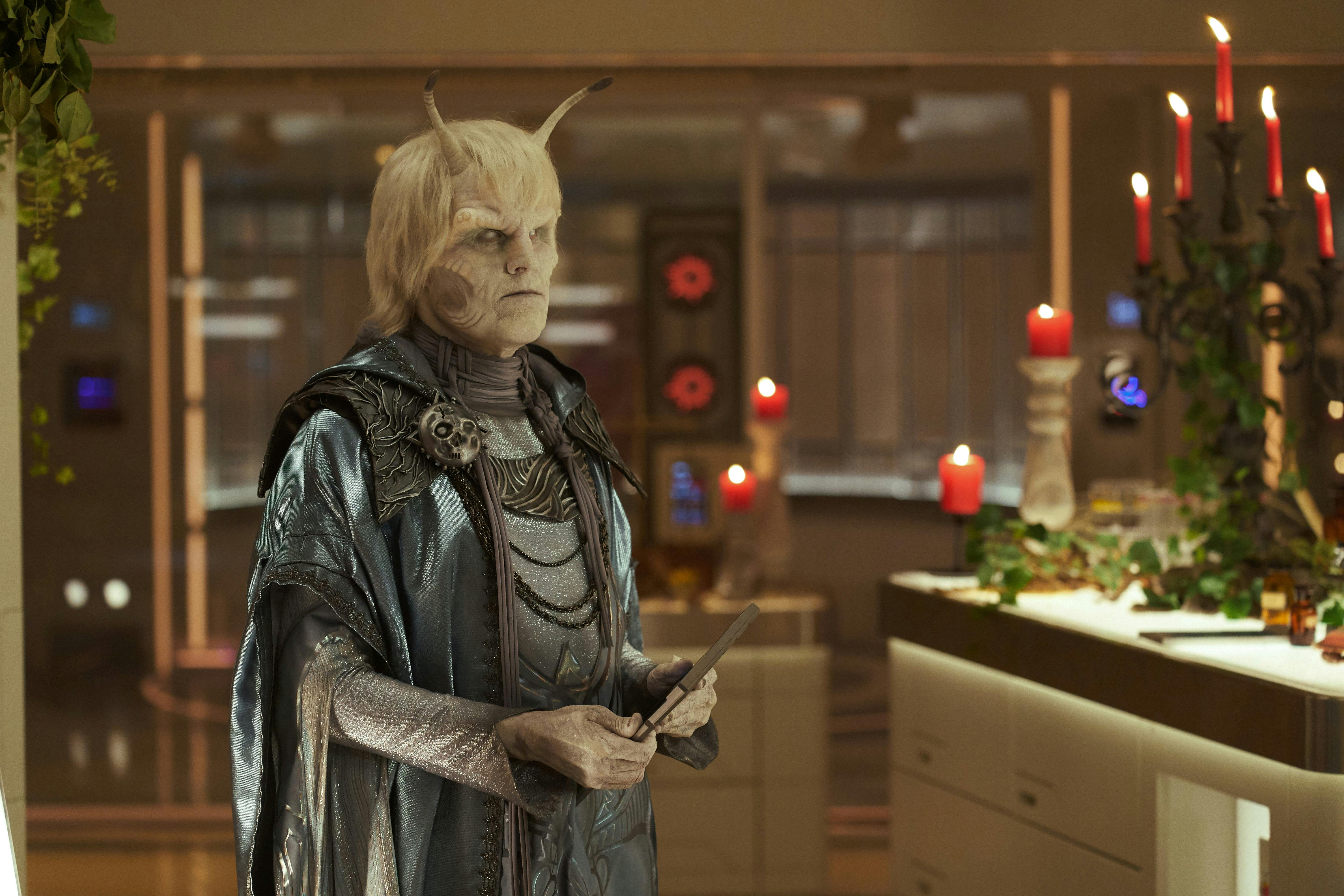 Hemmer (Bruce Horak), wearing elaborate robes, stands in the Enterprise's medbay. The medbay is lit with candles.