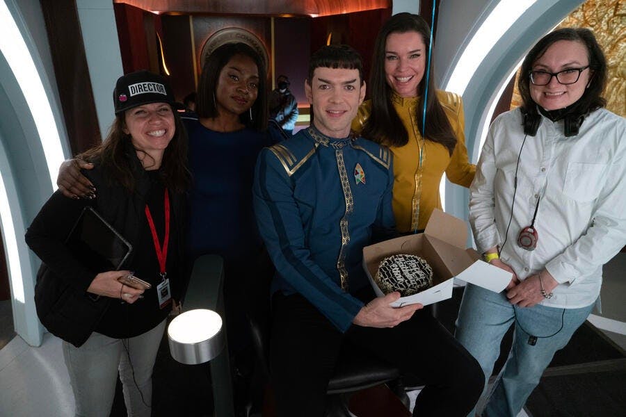 Behind-the-scenes of 'Ad Astra per Aspera' - Ethan Peck is presented with a birthday cake and is surrounded by Yetide Badaki, director Valerie Weiss, and Rebecca Romijn