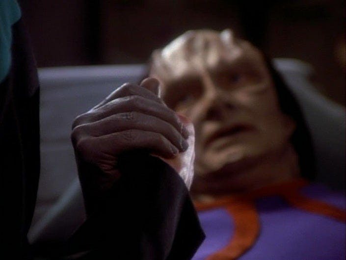 Garak holds Bashir's hand as he lays in the infirmary in 'The Wire'