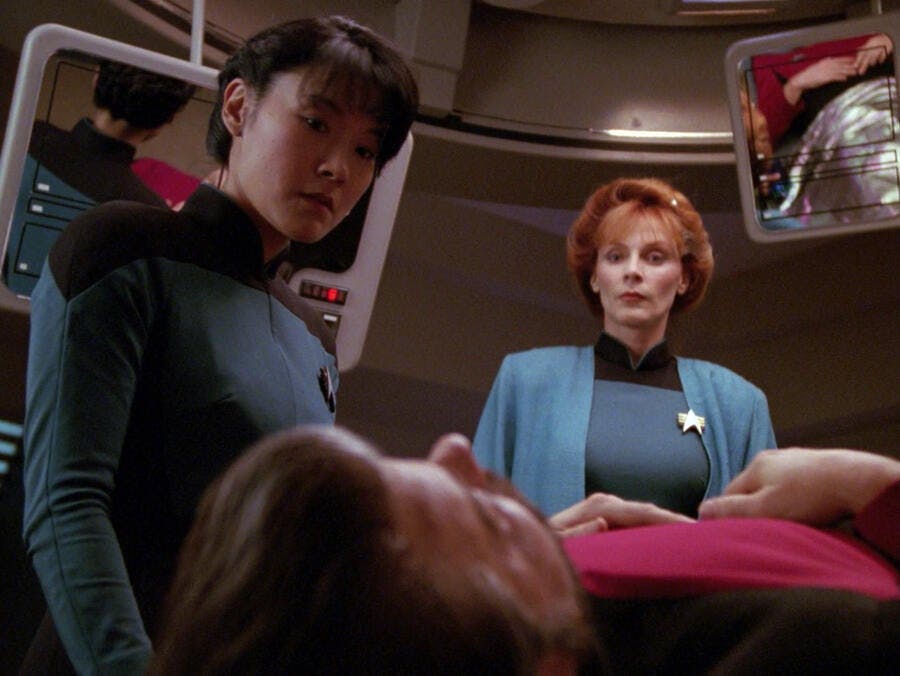 Nurse Alyssa Ogawa and Dr. Beverly Crusher monitor William Riker in Sickbay in 'Future Imperfect'
